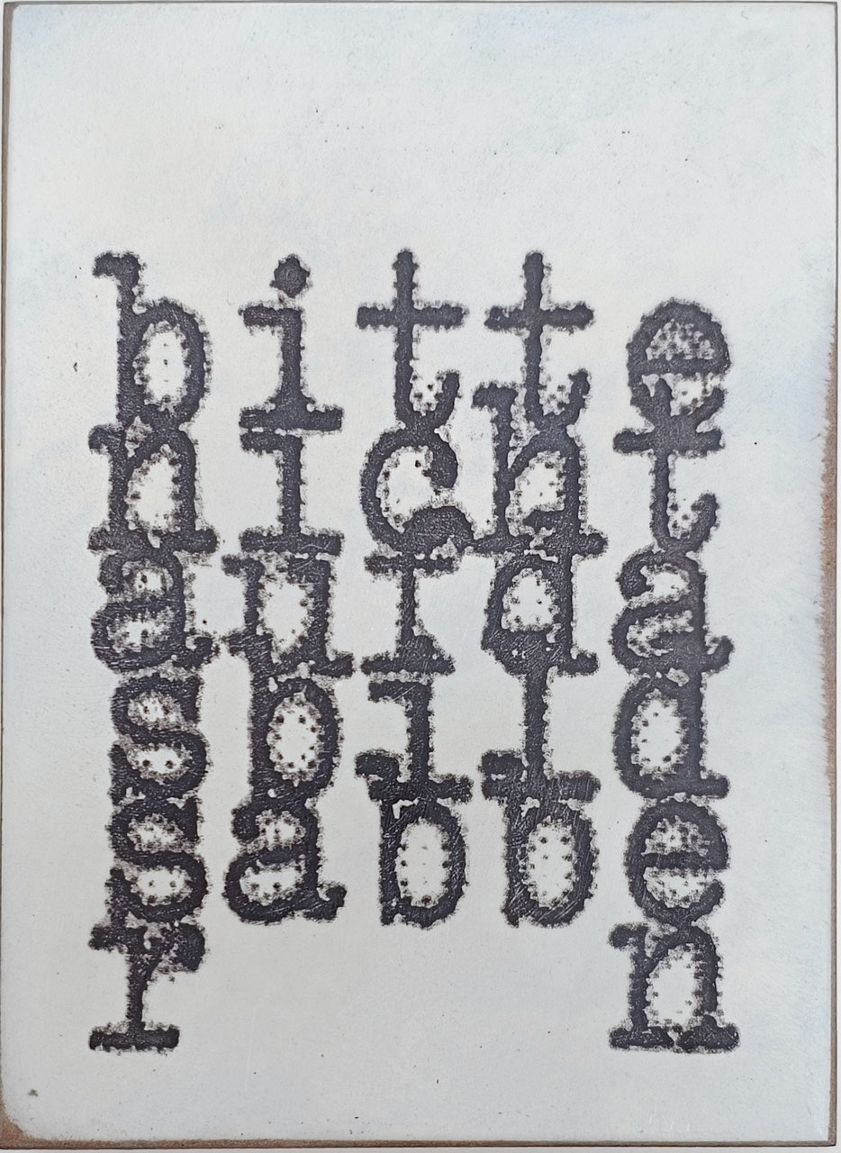 Objektkunst von Jan M. Petersen zeigt in groben an Schreibmaschine erinnernde Buchstaben die Wörter: bitte nicht auf das bild sabbern.