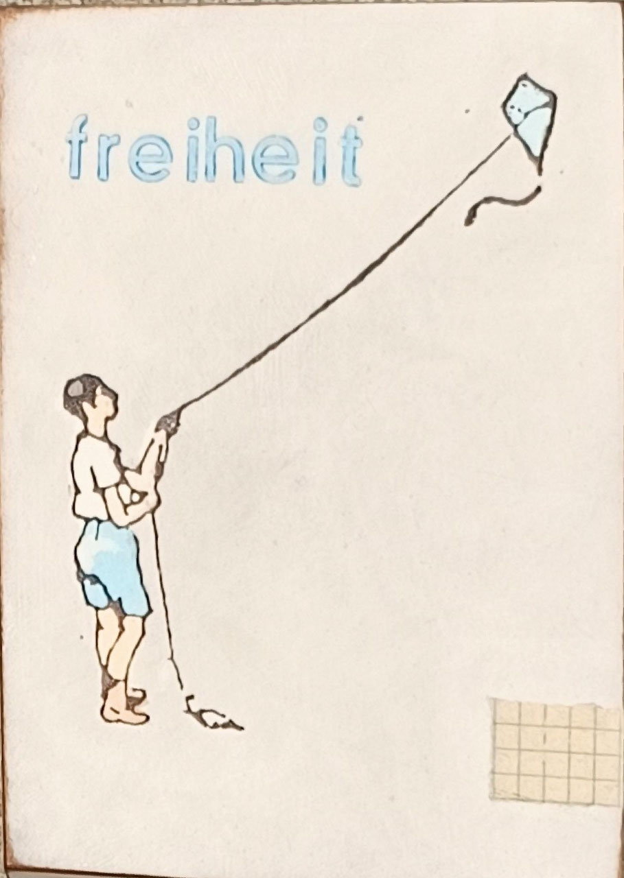 Objektkunst von Jan M. Petersen -freiheit- auf hellem Grund ein Junge in blauen Shorts, der einen Drachen steigen lässt, die Schnur spannt sich diagonal über das gesamte Bildfeld bis zum kleinen blauen Drachen oben rechts.