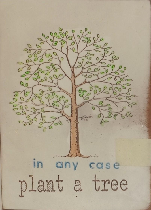 Objektkunst von Jan M. Petersen -in any case plant a tree- zeigt einen schlichten Baum mit kleinen grünen Blättern, darunter der Bildtitel in einfacher Schrift.